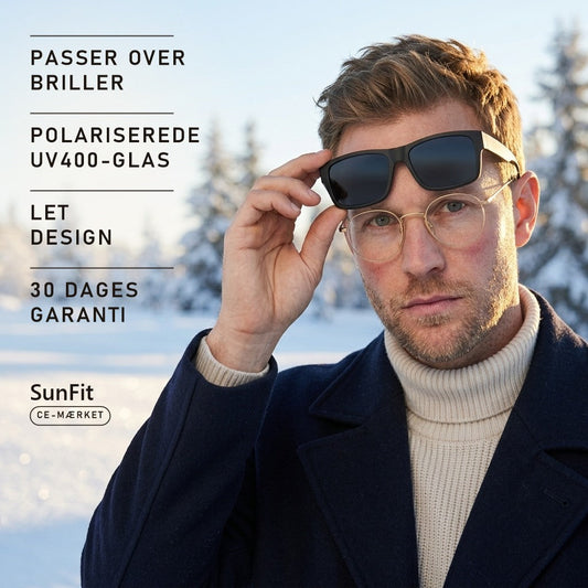 Mand med briller løfter SunFit fit-over-solbriller i vintersol over sne